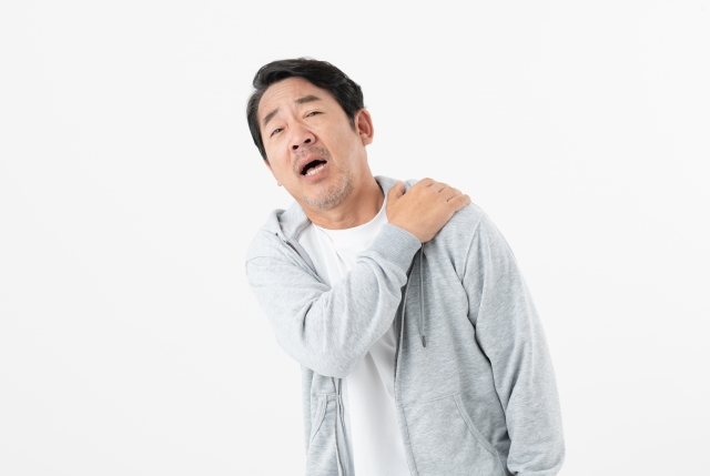 肩を押さえる中年の男性