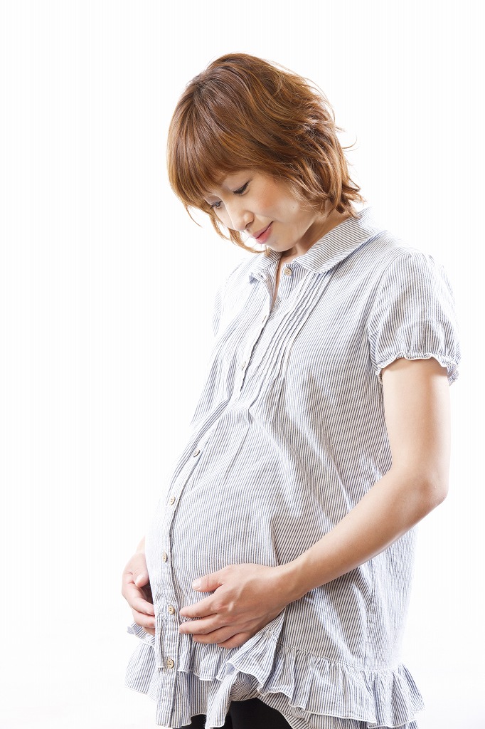 おなかに手を当てて立つ妊婦