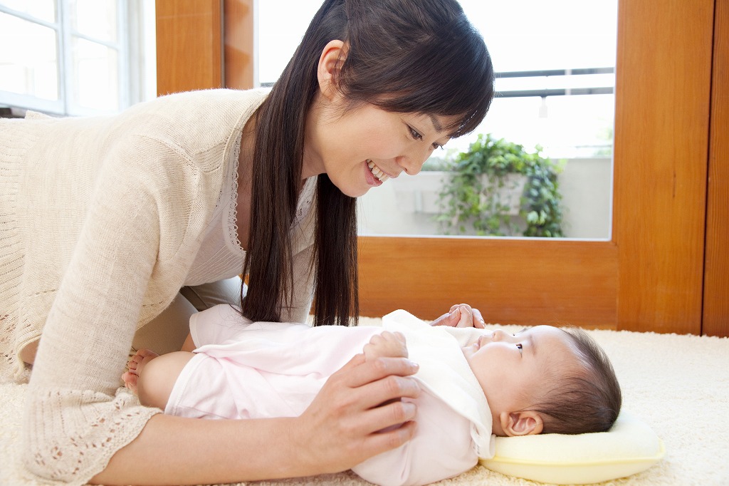 横になった赤ちゃんに寄り添う母親